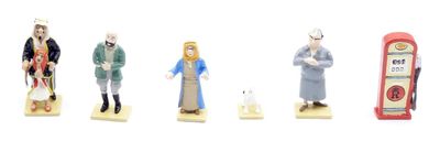 cinq figurines représentant des personnes debout devant une pompe à essence