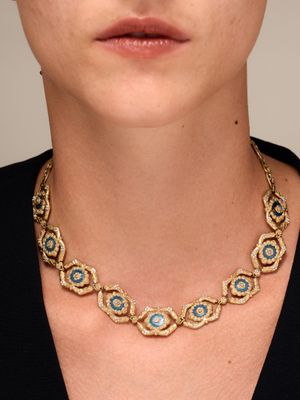 a close up of a woman wearing a necklace with blue stones on it