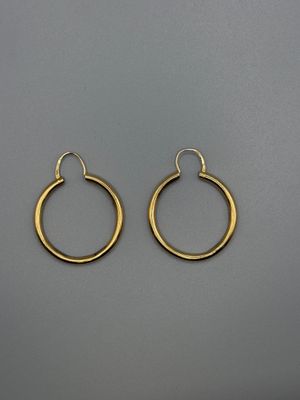 une paire de boucles d'oreilles créoles en or sur fond gris