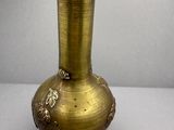 un vase en or posé sur une table, sur fond blanc