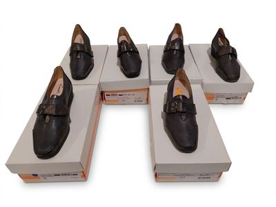 Six paires de chaussures noires sont exposées dans une boîte