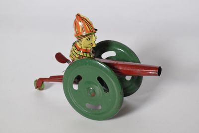 un petit jouet représentant un pompier sur une roue verte
