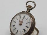 a silver pocket watch with roman numerals on it