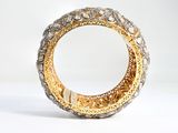 a close up of a gold and silver bracelet on a white surface