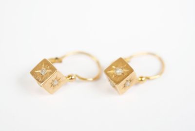 a pair of gold earrings with diamonds on them on a white surface