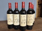 four bottles of wine are lined up on a wooden table