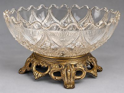 un bol en verre ancien posé sur un socle, sur une surface grise