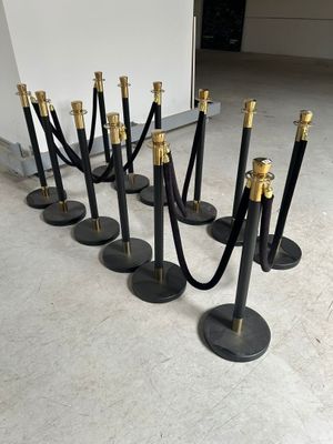 un ensemble de poteaux de délimitation noirs et dorés, entourés d'une corde