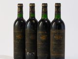 quatre bouteilles de vin sont alignées sur une surface blanche