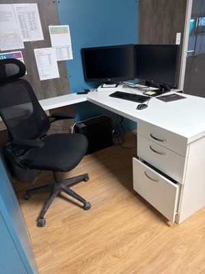 un bureau blanc avec une chaise noire et un ordinateur posé dessus