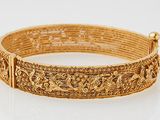 a close up of a gold bracelet on a white surface