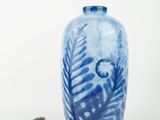 a blue and white vase with a measuring tape next to it