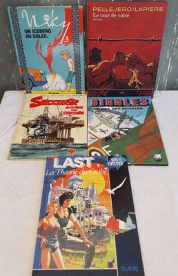 Plusieurs livres sont alignés sur une table devant un mur.
