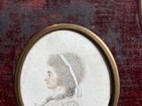 three framed portraits of women in old fashions on a red velvet surface