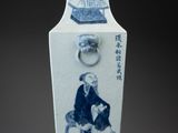 a blue and white vase with a picture of a man sitting on a chair