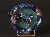 a close up of a blue and green plate with a bird on it