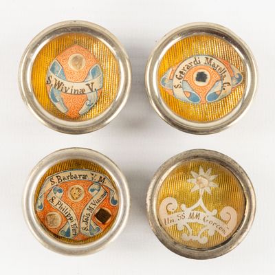 four small metal buttons with different designs on them on a white surface