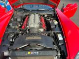 a red sports car with its hood open and the engine in it ' s trunk