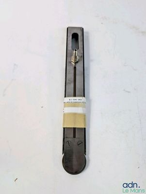une image représentant un objet métallique posé sur une surface blanche, avec un morceau de ruban adhésif