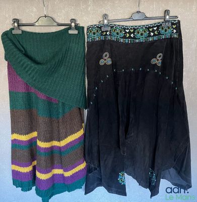 two skirts hanging on a clothes rack with a scarf on it
