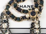 a close up of a chanel necklace with pearls and a chain