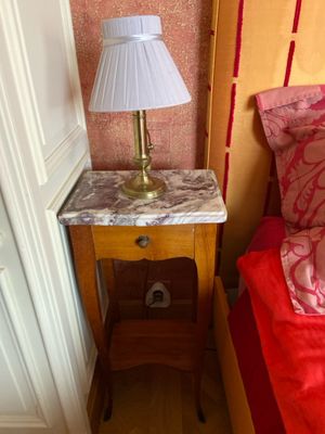 une petite table sur laquelle est posée une lampe, à côté d'un lit