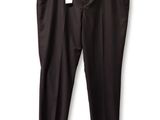 Le pantalon noir est suspendu à un cintre accroché à un mur blanc.