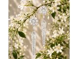 a pair of diamond earrings on a branch with flowers in the background