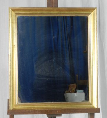 un miroir posé sur un socle en bois, avec un rideau bleu en arrière-plan