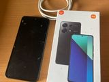 a box of redmi note 13 next to a charger on a table