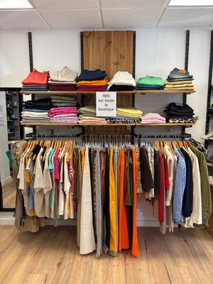 un portemanteau dans un magasin de vêtements, sur lequel est accrochée une pancarte