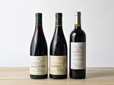 trois bouteilles de vin sont alignées sur une table en bois