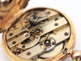 a close up of a pocket watch on a white surface