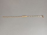 gros plan d'un bracelet en or sur une surface grise