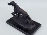 a bronze statue of a dog on a surfboard on a marble base
