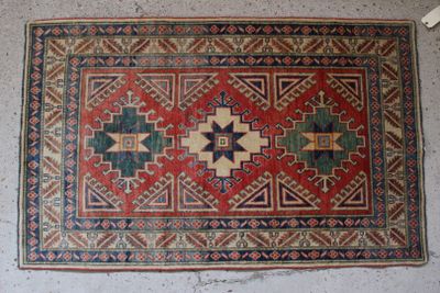 un vieux tapis posé à même le sol, avec un mur blanc en arrière-plan