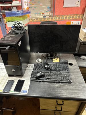 a desk with a computer, keyboard, mouse, and other items on it