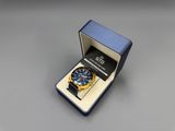 a blue and yellow watch in a blue box on a gray surface