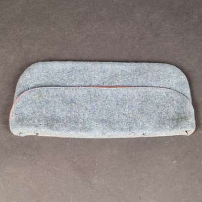 un gros plan d'une trousse en feutre gris posée sur une surface marron