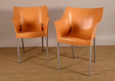 une paire de fauteuils en cuir orange aux pieds chromés, posés sur un espace recouvert de moquette