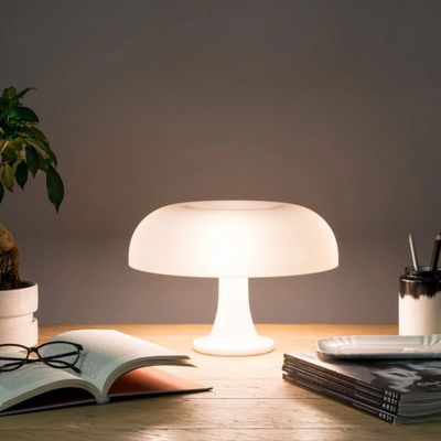 the lamp is sitting on a table next to a book and a plant
