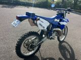 a blue and white dirt bike parked in a parking lot