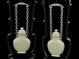 paire de vases chinois en jade sculpté, munis de chaînes et posés sur des socles