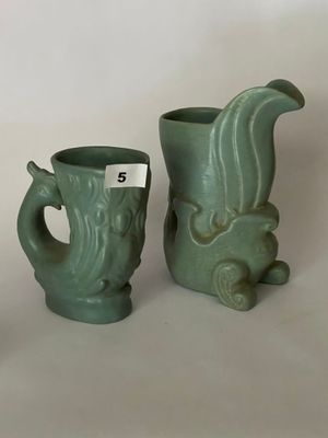 deux vases verts posés l'un à côté de l'autre sur une table