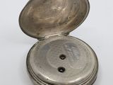 an old silver pocket watch sitting on top of a white surface