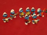 several figurines of the smurfs are lined up on a red surface