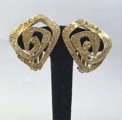 pair of vintage gold tone earrings on a black stand