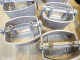 four metal buckets are sitting on a wooden table with springs