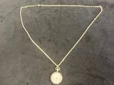 a gold necklace with a white pearl on a chain