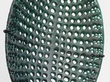 un panier vert perforé posé sur une surface blanche